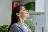 Person taking deep inhale of clean indoor air after duct cleaning in Ocean County